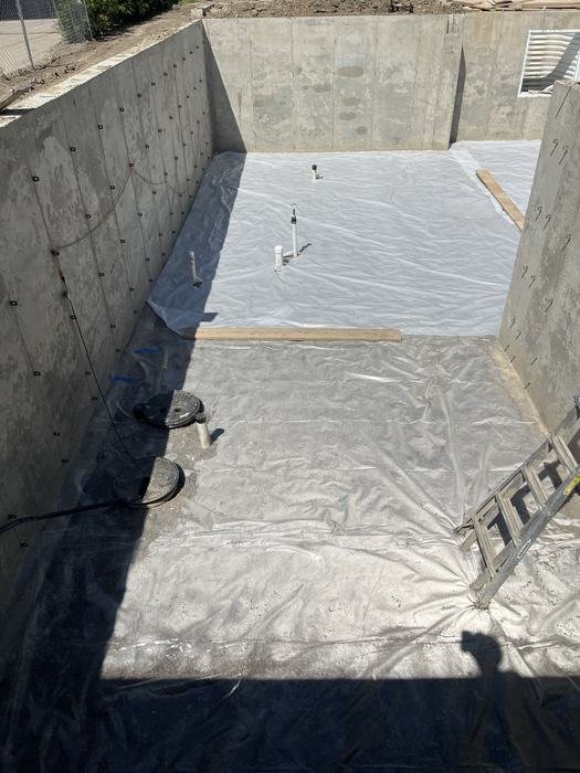 Poured concrete foundation walls with vapor barrier laid over the basement floor